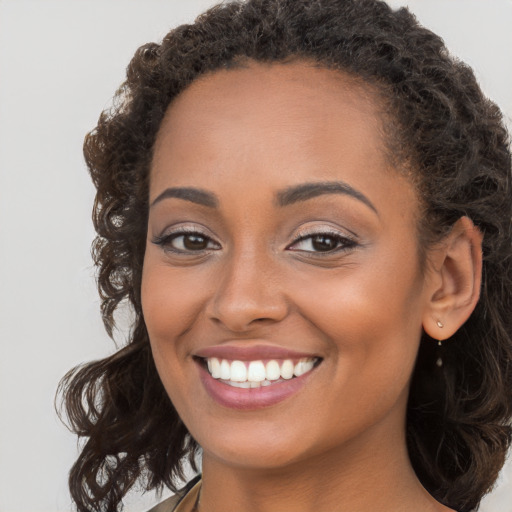 Joyful black young-adult female with long  brown hair and brown eyes