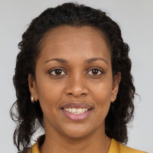 Joyful black young-adult female with long  brown hair and brown eyes