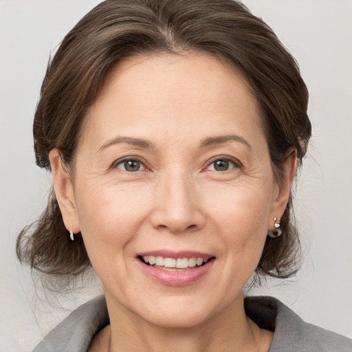 Joyful white adult female with medium  brown hair and grey eyes