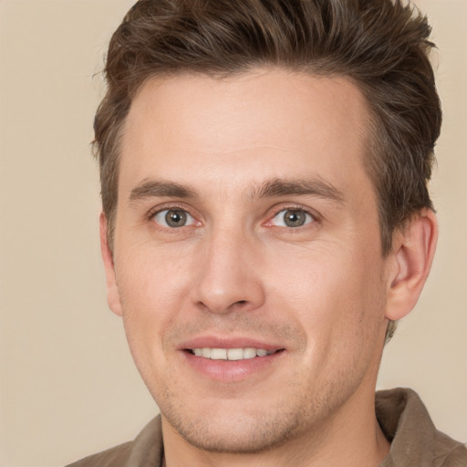 Joyful white young-adult male with short  brown hair and grey eyes