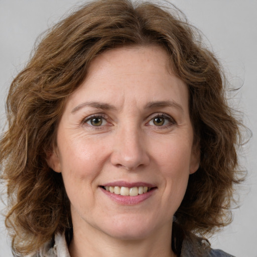 Joyful white adult female with medium  brown hair and green eyes