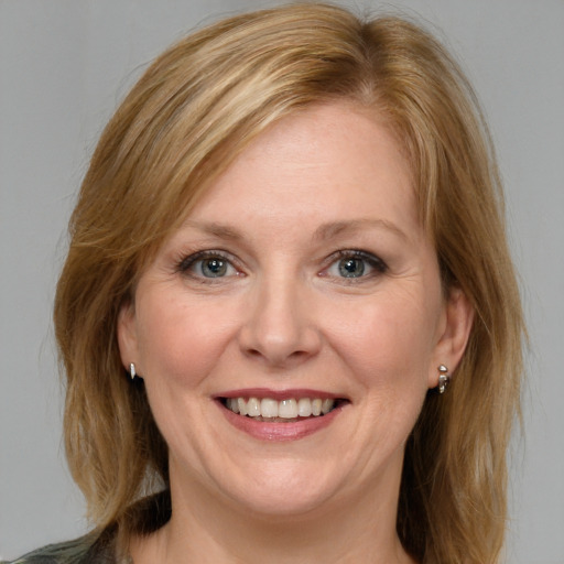 Joyful white adult female with medium  brown hair and blue eyes