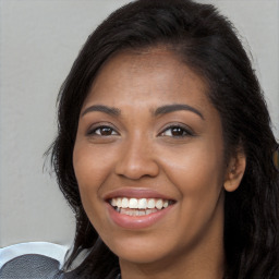 Joyful black young-adult female with long  brown hair and brown eyes