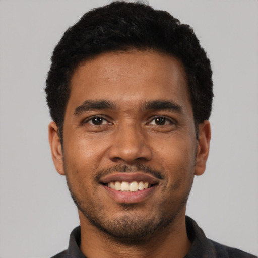 Joyful black young-adult male with short  black hair and brown eyes