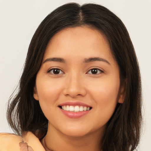 Joyful latino young-adult female with long  brown hair and brown eyes