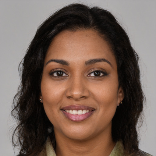 Joyful black young-adult female with long  brown hair and brown eyes
