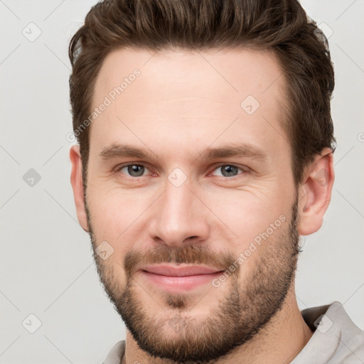 Joyful white young-adult male with short  brown hair and grey eyes