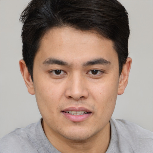 Joyful asian young-adult male with short  brown hair and brown eyes
