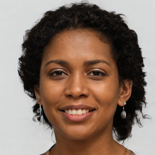 Joyful black young-adult female with long  black hair and brown eyes