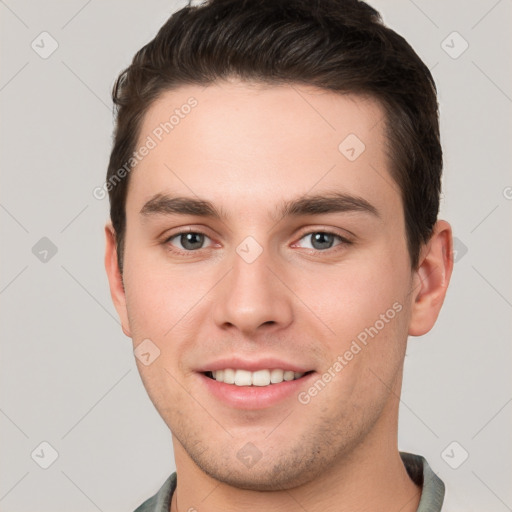 Joyful white young-adult male with short  brown hair and grey eyes