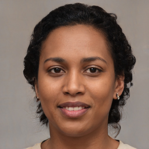Joyful black young-adult female with medium  black hair and brown eyes