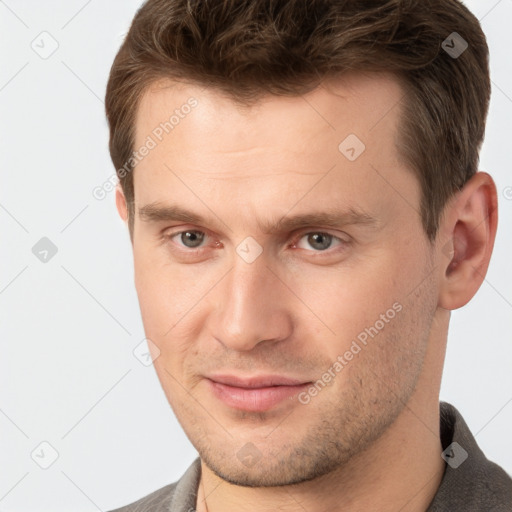 Joyful white young-adult male with short  brown hair and grey eyes