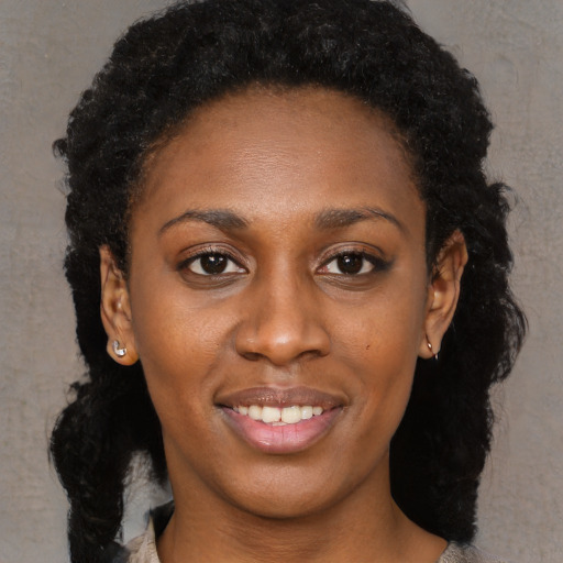 Joyful black young-adult female with long  black hair and brown eyes