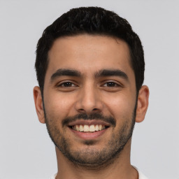 Joyful latino young-adult male with short  black hair and brown eyes