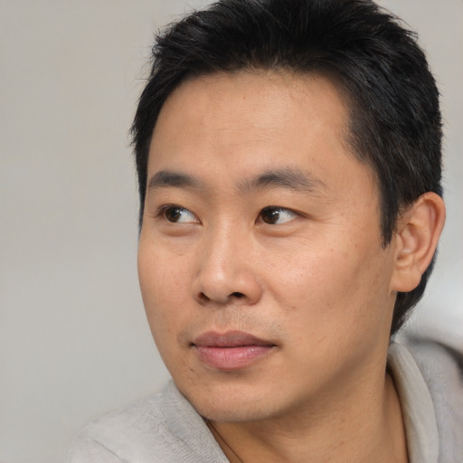 Joyful asian young-adult male with short  brown hair and brown eyes