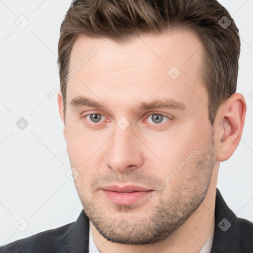 Joyful white young-adult male with short  brown hair and grey eyes