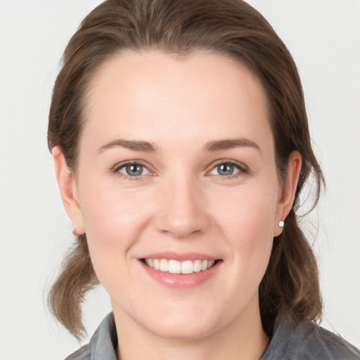 Joyful white young-adult female with medium  brown hair and grey eyes