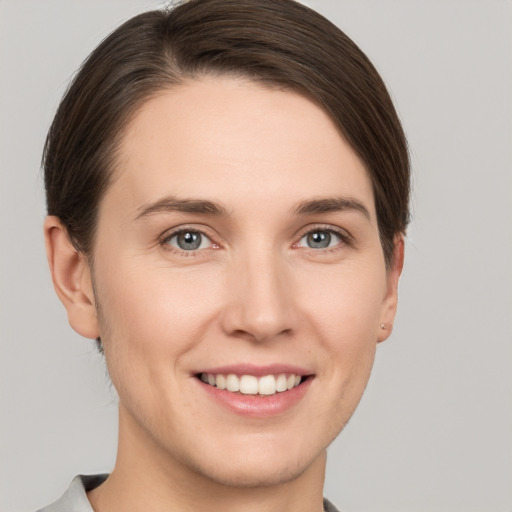 Joyful white young-adult female with short  brown hair and grey eyes