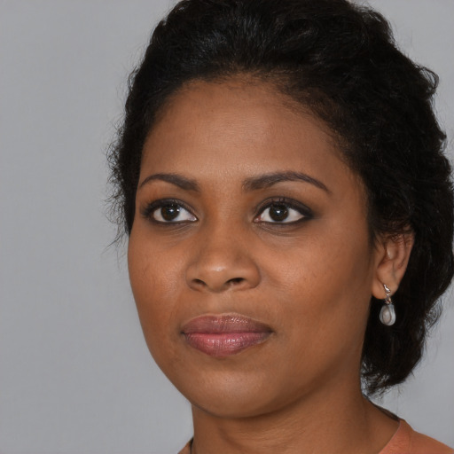 Joyful black young-adult female with long  black hair and brown eyes