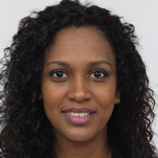 Joyful black young-adult female with long  brown hair and brown eyes