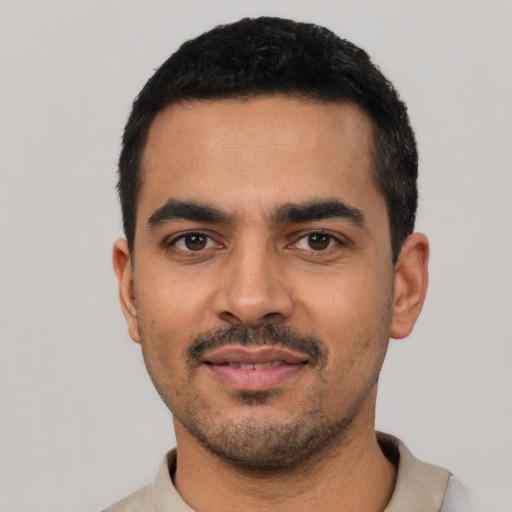 Joyful latino young-adult male with short  black hair and brown eyes