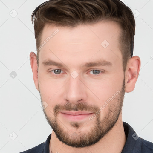 Joyful white young-adult male with short  brown hair and grey eyes