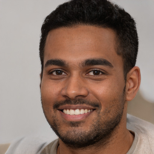 Joyful black young-adult male with short  black hair and brown eyes