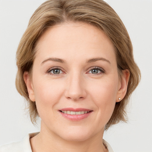 Joyful white young-adult female with medium  brown hair and grey eyes