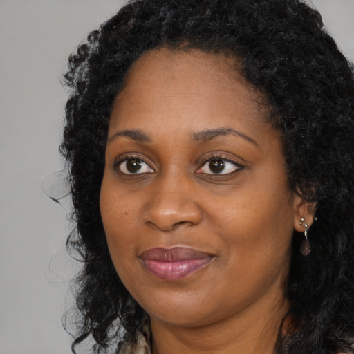 Joyful black young-adult female with long  black hair and brown eyes