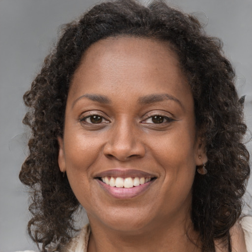 Joyful black adult female with long  brown hair and brown eyes