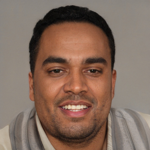 Joyful black young-adult male with short  black hair and brown eyes