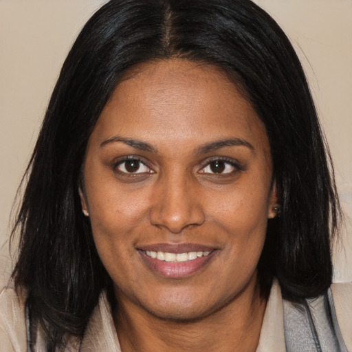 Joyful black young-adult female with long  brown hair and brown eyes