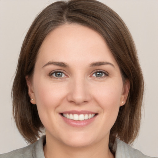 Joyful white young-adult female with medium  brown hair and grey eyes