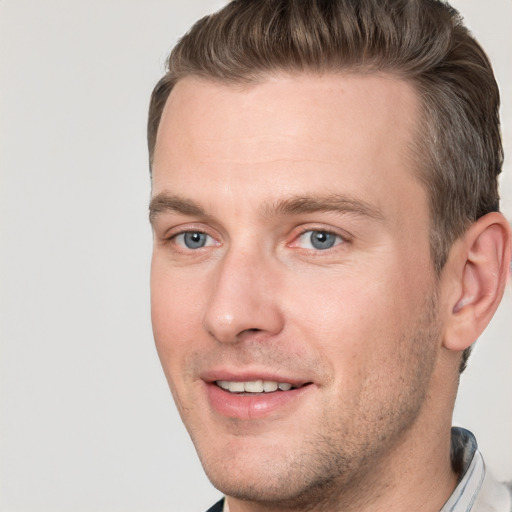 Joyful white young-adult male with short  brown hair and grey eyes