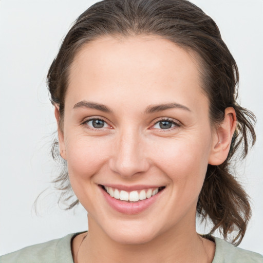 Joyful white young-adult female with medium  brown hair and grey eyes