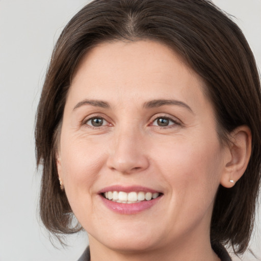 Joyful white young-adult female with medium  brown hair and grey eyes