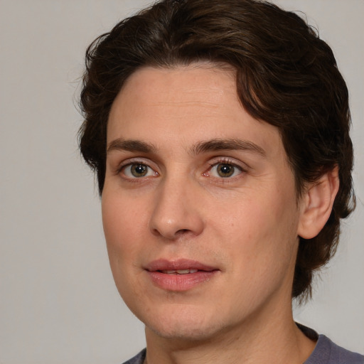 Joyful white young-adult male with medium  brown hair and green eyes