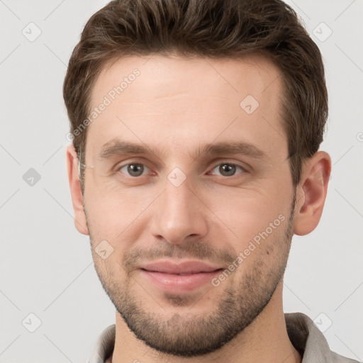 Joyful white young-adult male with short  brown hair and grey eyes