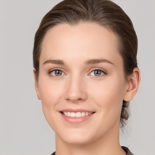 Joyful white young-adult female with medium  brown hair and grey eyes