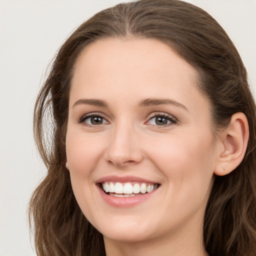 Joyful white young-adult female with long  brown hair and grey eyes