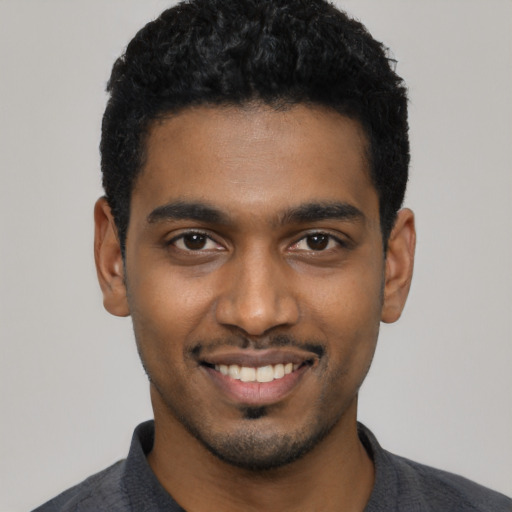 Joyful black young-adult male with short  black hair and brown eyes