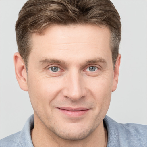 Joyful white young-adult male with short  brown hair and grey eyes