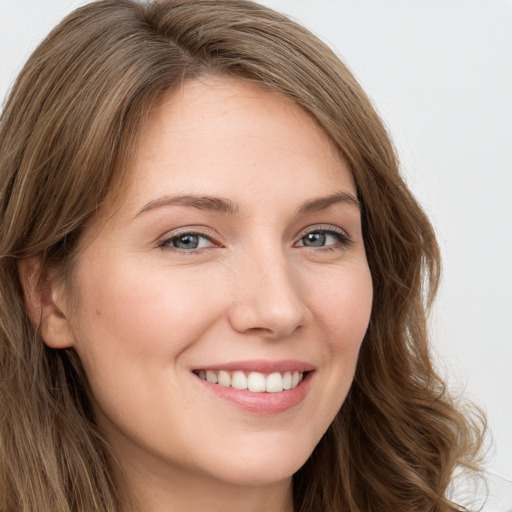 Joyful white young-adult female with long  brown hair and blue eyes