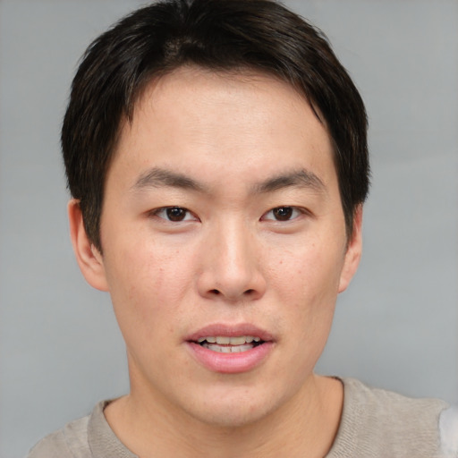 Joyful asian young-adult male with short  brown hair and brown eyes