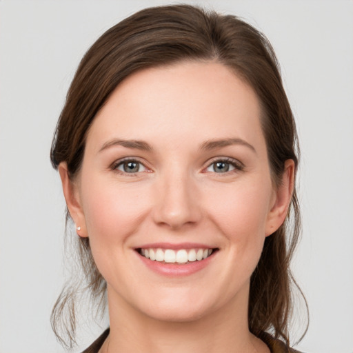 Joyful white young-adult female with medium  brown hair and grey eyes