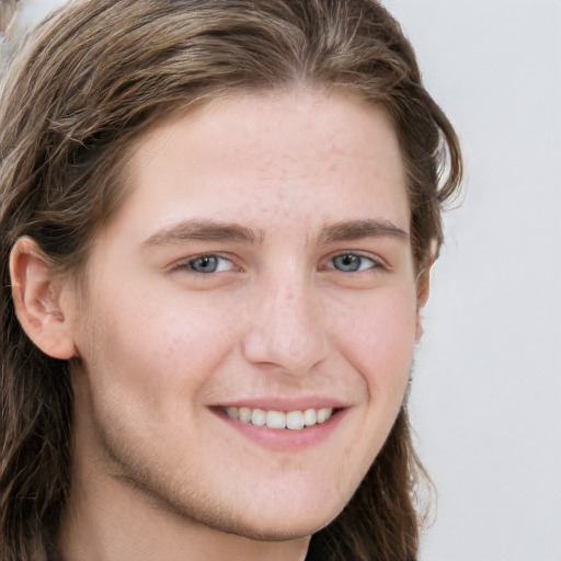 Joyful white young-adult male with long  brown hair and grey eyes