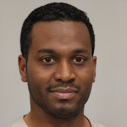Joyful black young-adult male with short  black hair and brown eyes