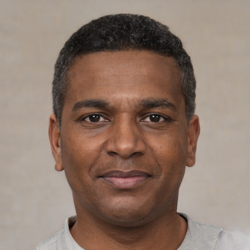 Joyful black young-adult male with short  black hair and brown eyes