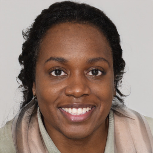 Joyful black young-adult female with long  brown hair and brown eyes