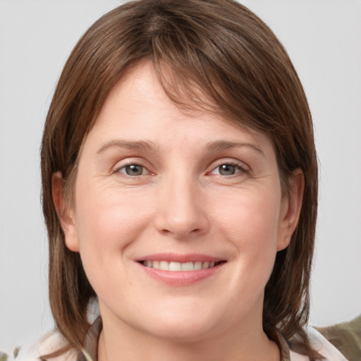 Joyful white young-adult female with medium  brown hair and grey eyes